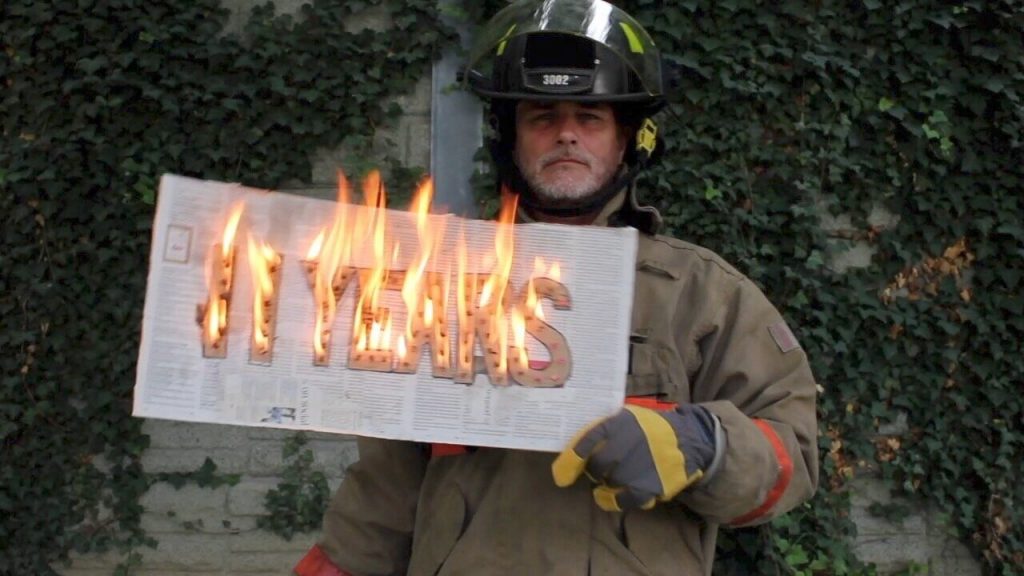 Image of Paul Gross dressed as a fire fighter to draw attention to the climate emergency