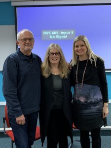 Dr. Kathleen Gallagher, Dr. Rachel Turner-King and Professor Jonothon Neelands posing in front of a projector screen after a presentation