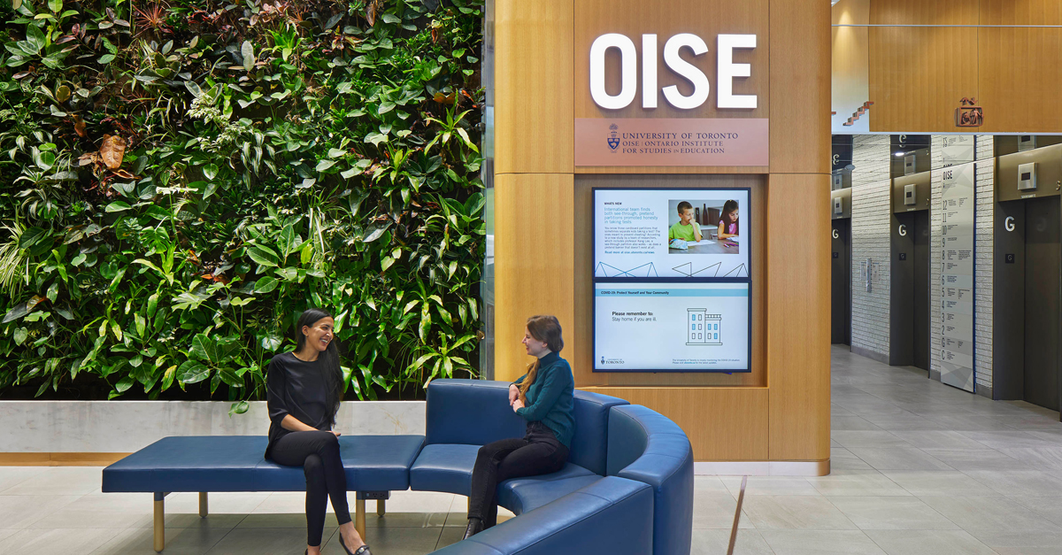 Two individuals sitting in the OISE lobby