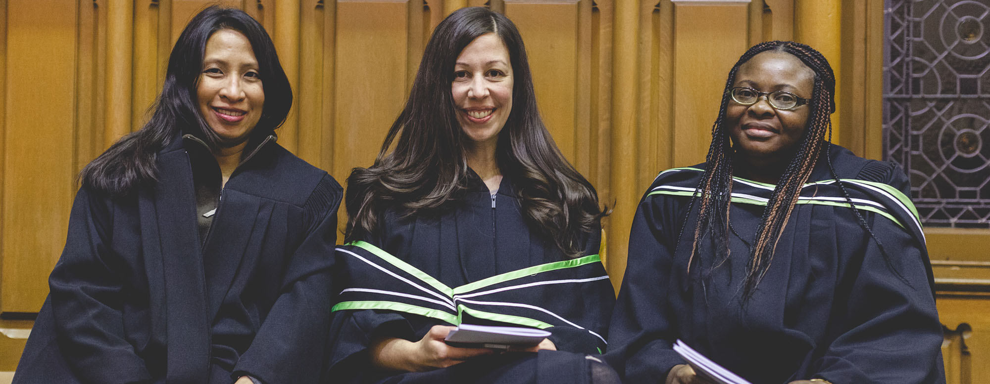 Three students seated and smiling at OISE convocation 