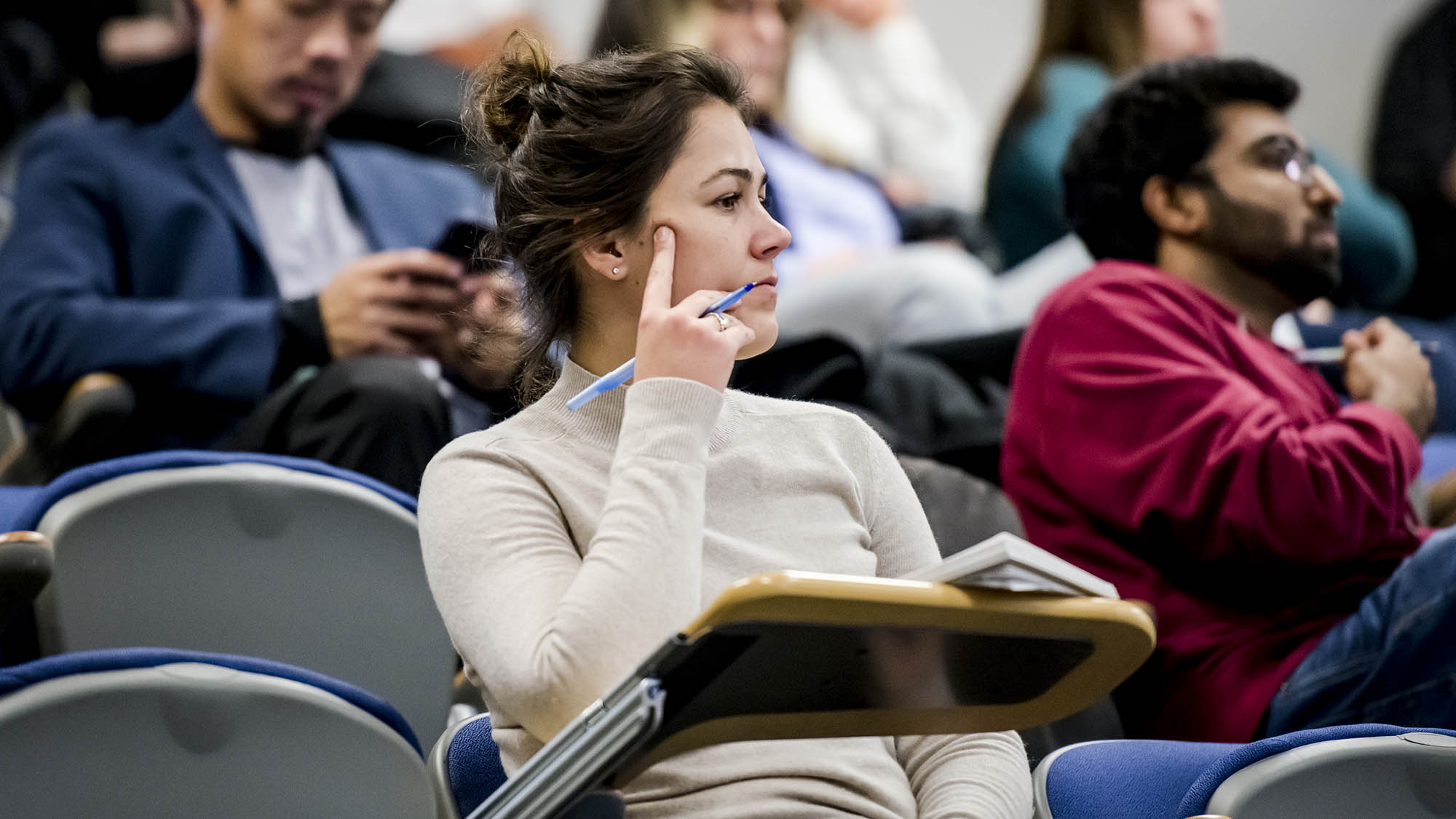 A student listening intently in a lecture hall. 