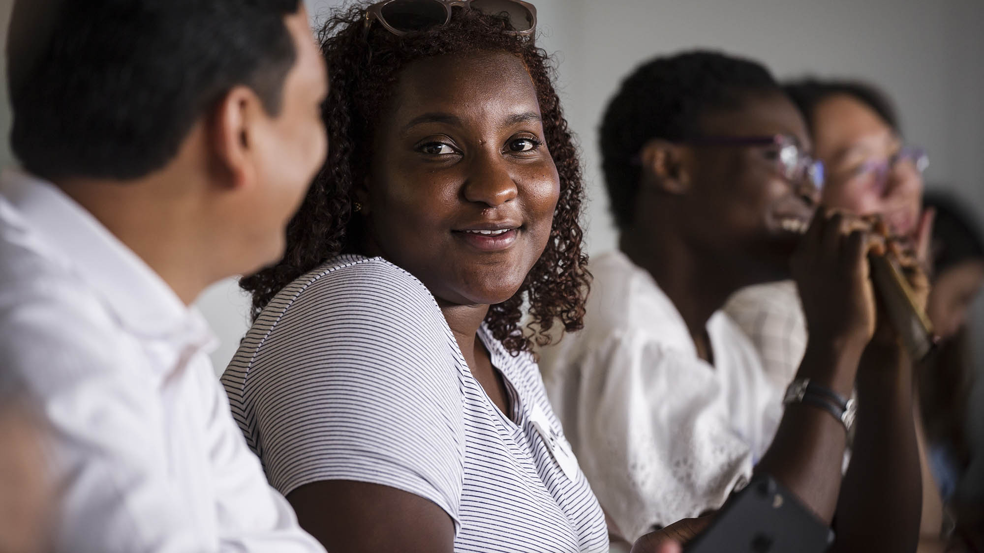 Four students talking in a classroom. One is looking directly at the camera.