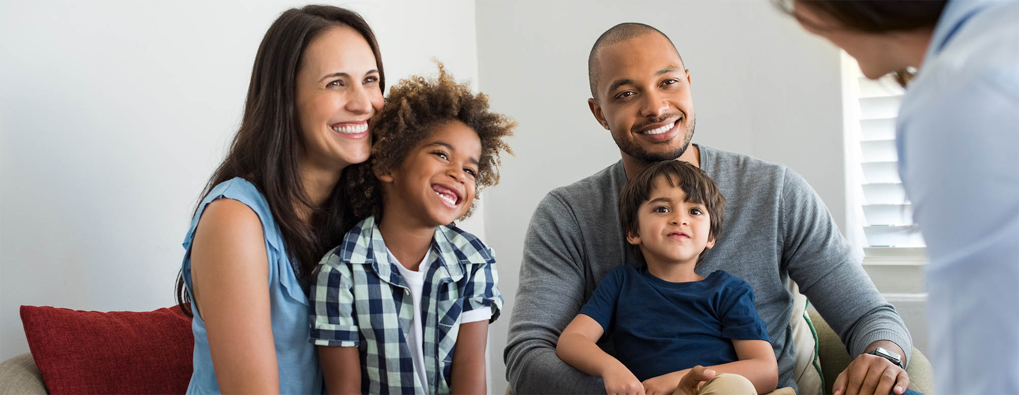 A family of four talking to seated on a couch and smiling.