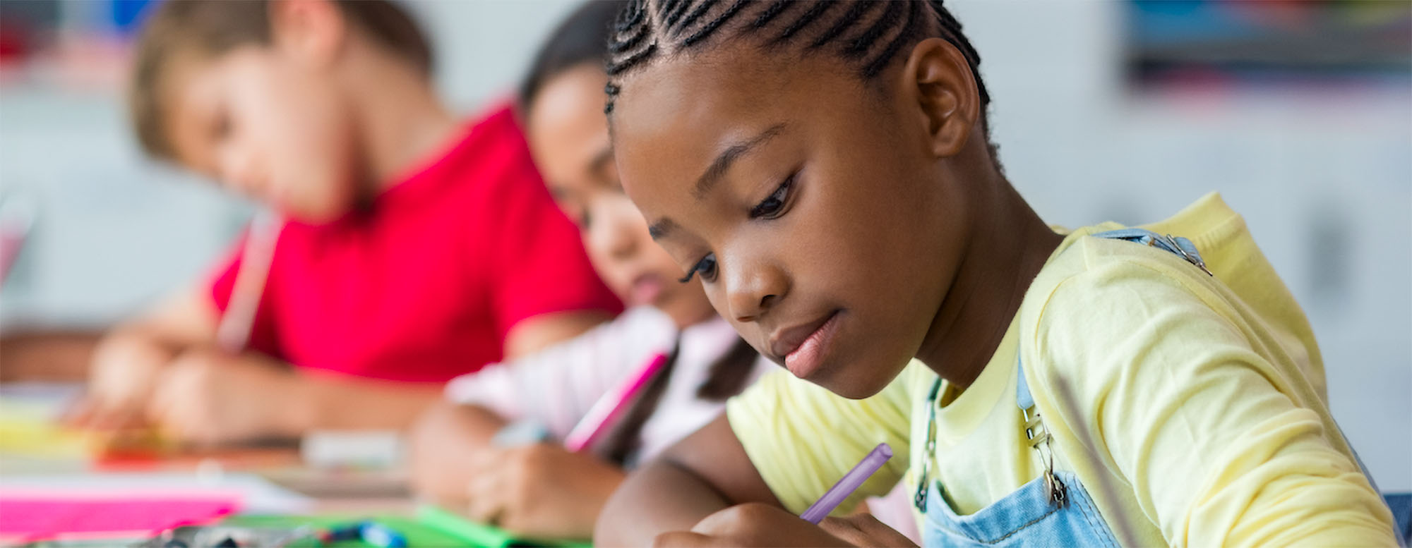 A grade school student taking notes in a classroom.