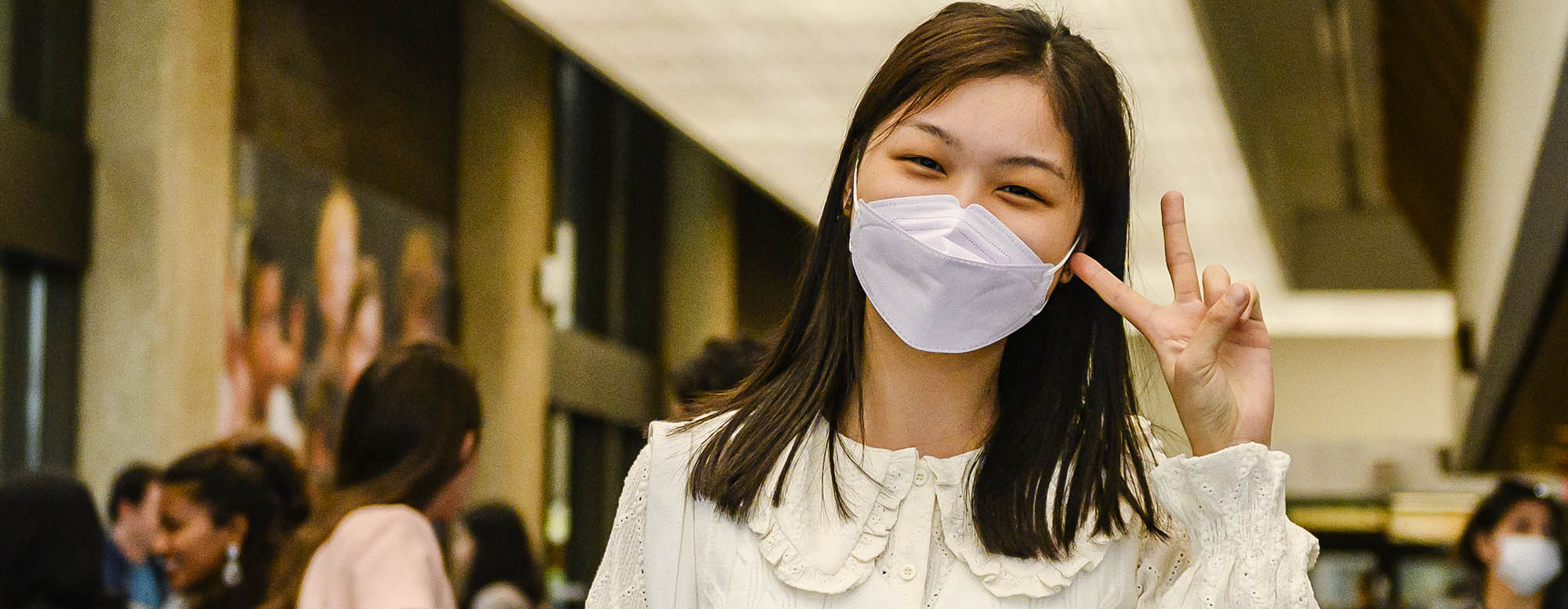 A student smiling under a facial mask.