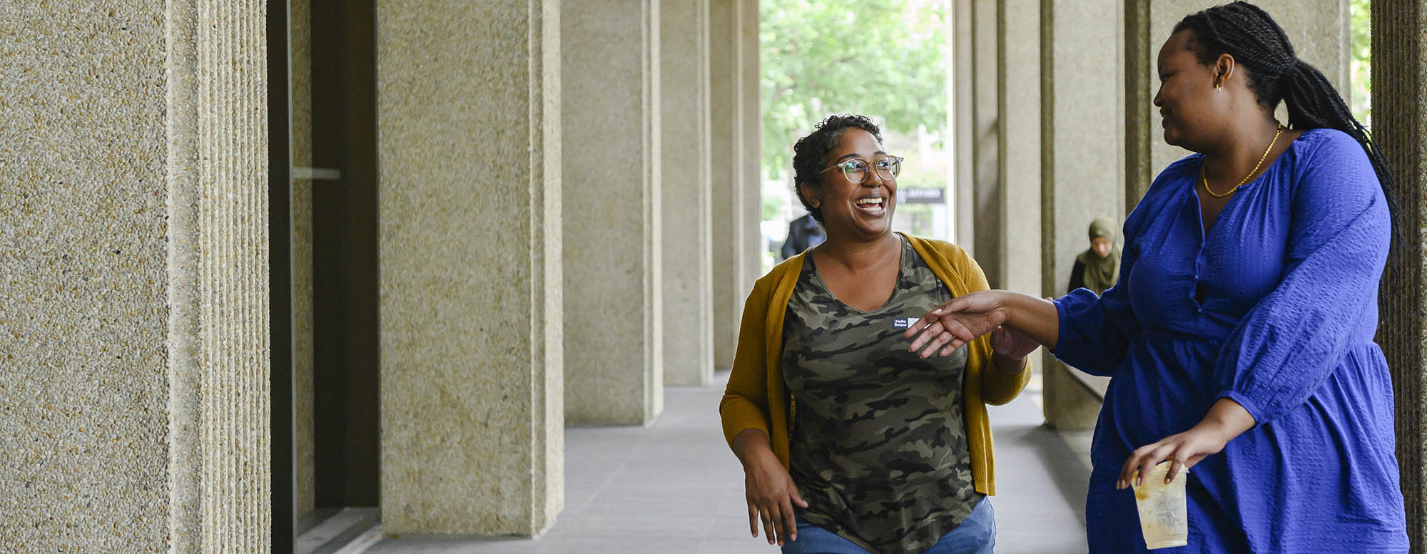 Two students smiling and walking outside the OISE building.