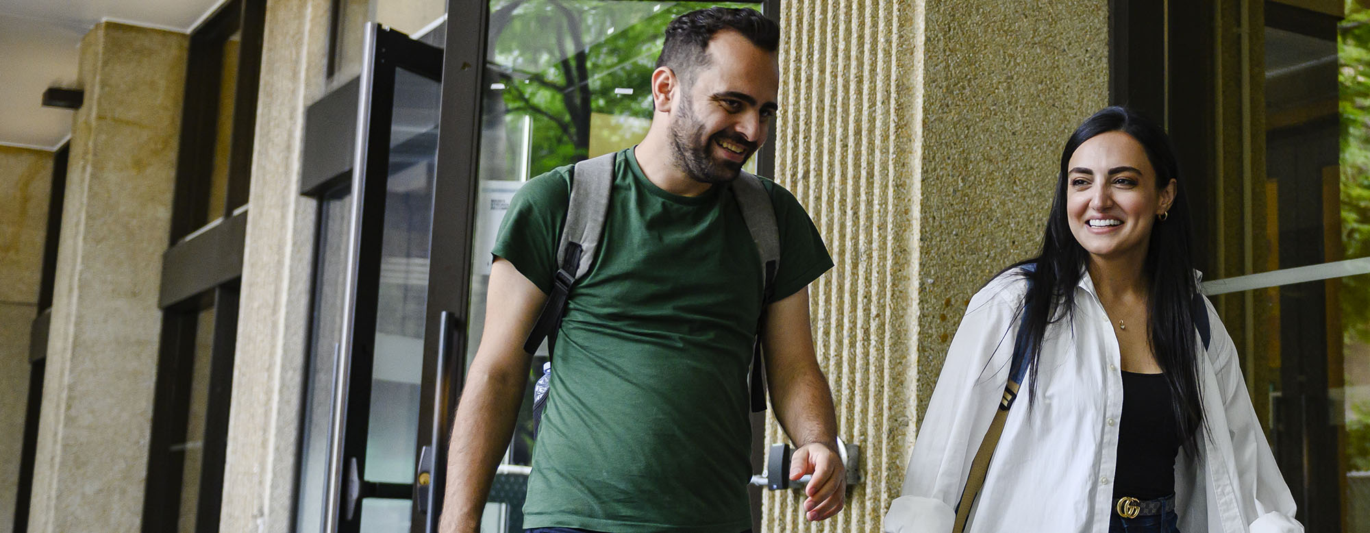 Two students walking outside the OISE building.