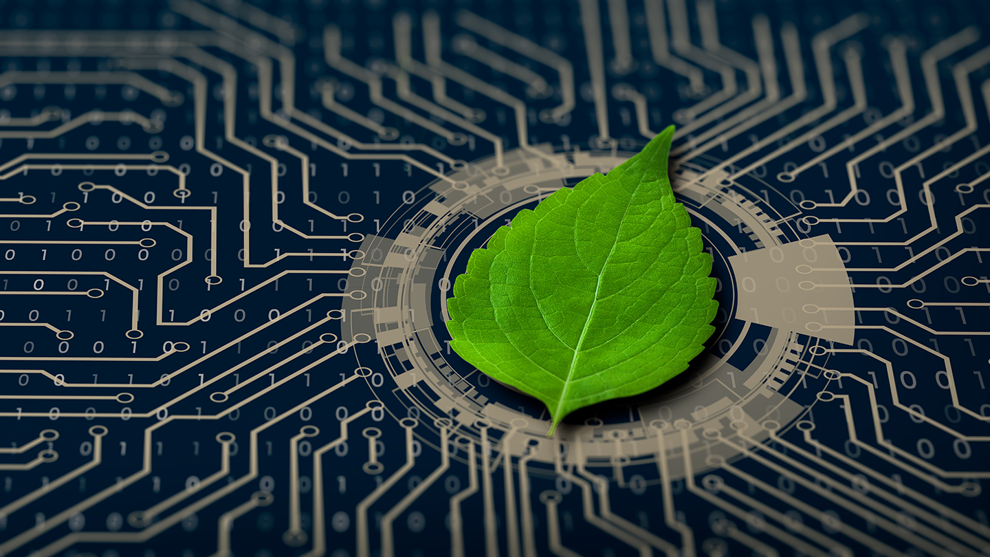 A bright green leaf lies on a blue-and-silver circuit board, symbolizing green technology.