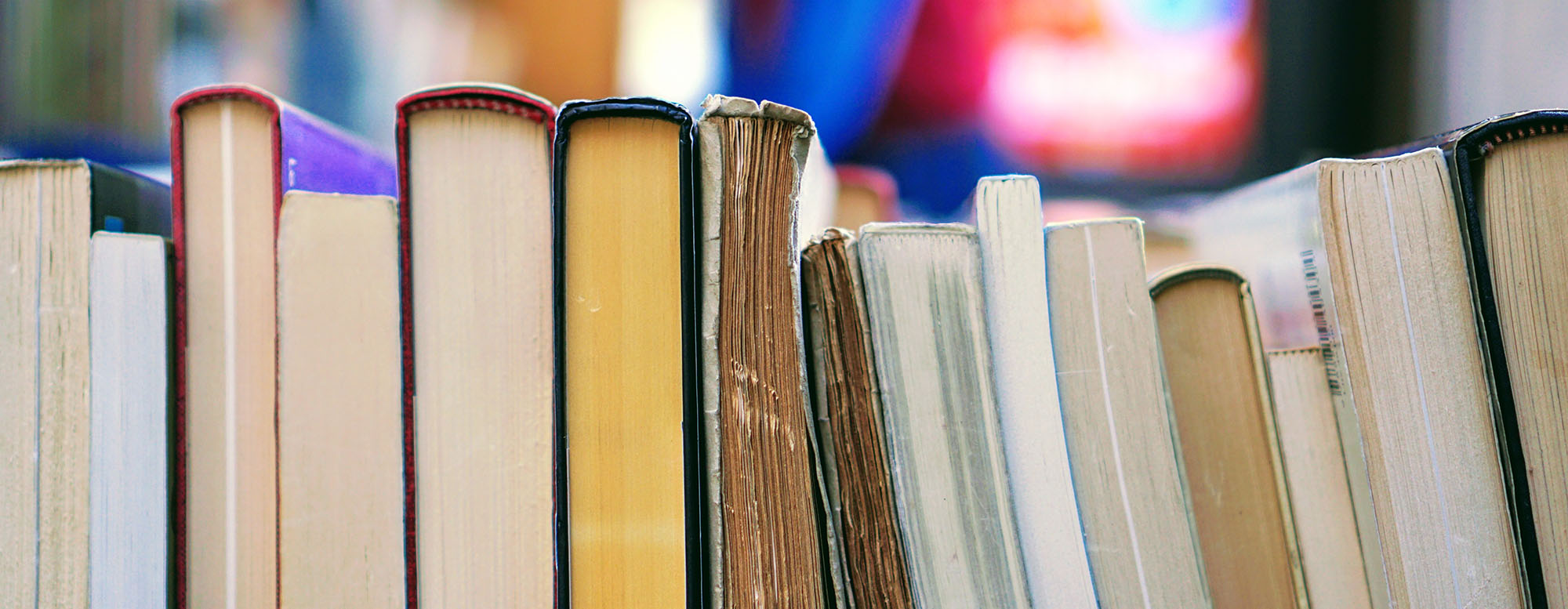 A bunch of books stacked sideways on a shelf.