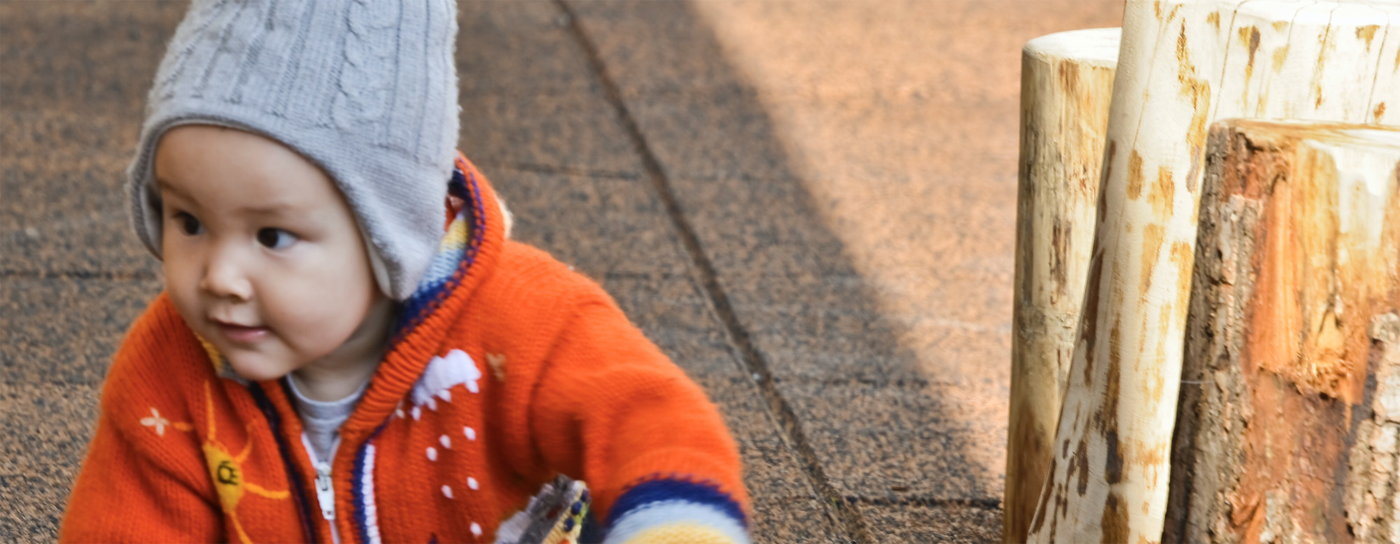 A baby crawling outside in a playground.