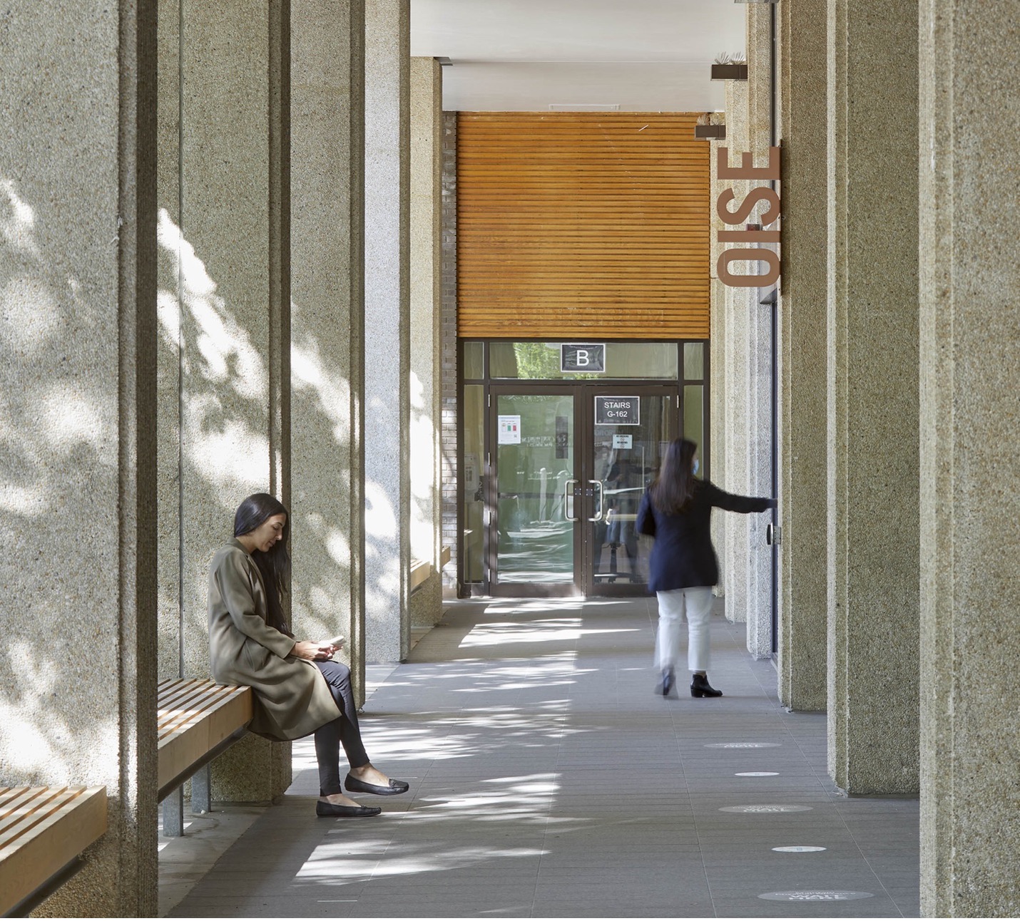 two female students in OISE walkway entrance