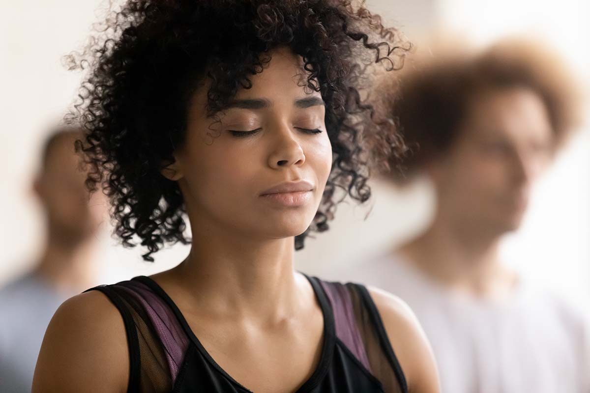 A Black student is sitting with her eyes closed and practicing mindfulness in a classroom setting