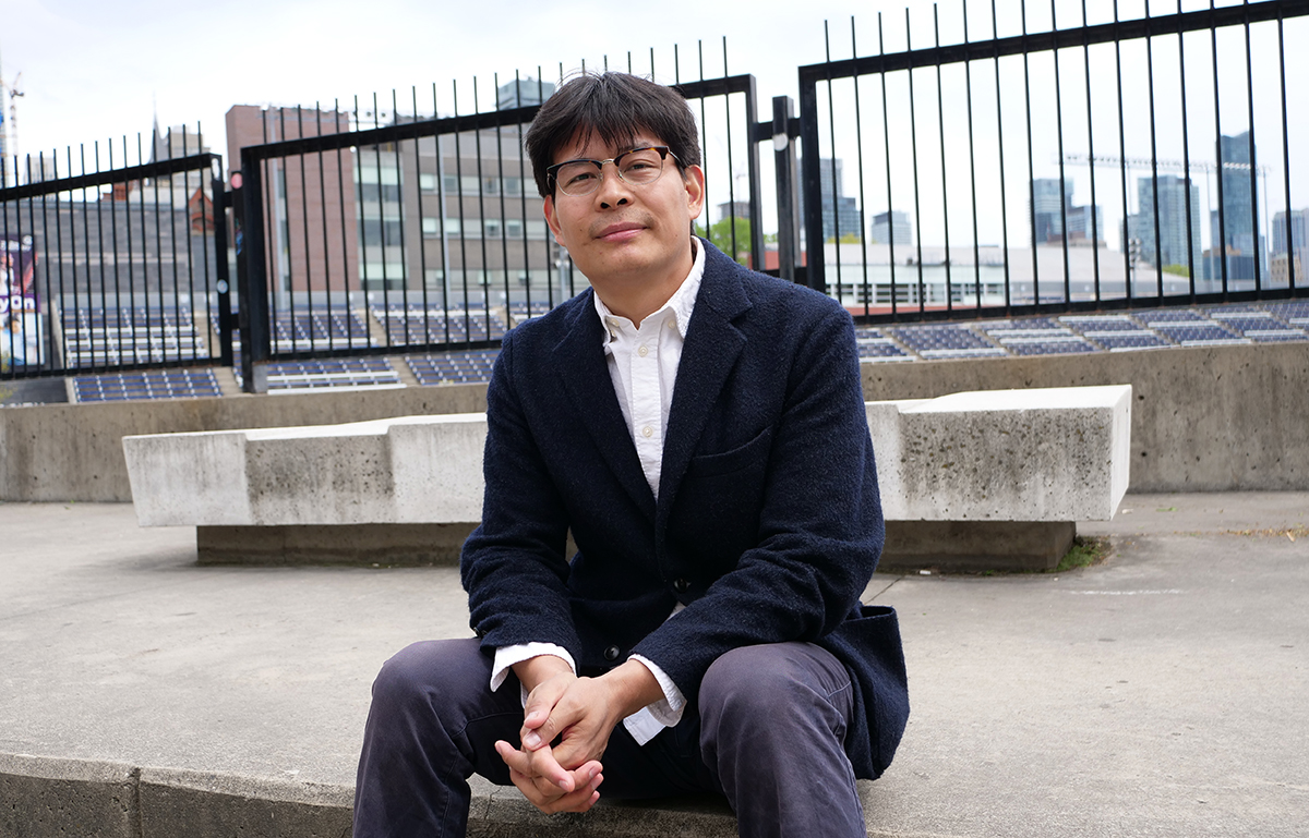 Nan La, a tibetan student presenting as a man, is sitting in front varsity stadium at the University of Toronto