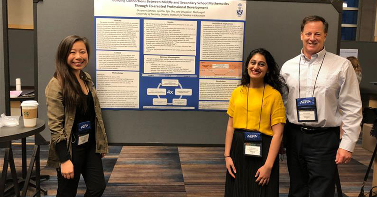 Three individuals stand in front of a research poster, smiling.