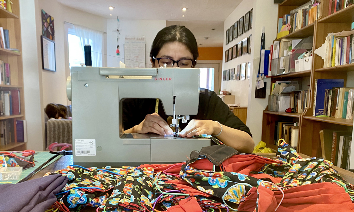 A woman with a sewing machine, making masks.