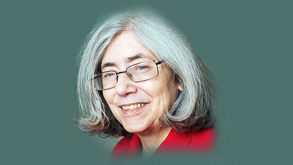 Woman with short grey hair and red top, smiling.