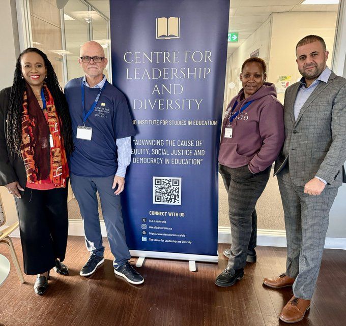 Image of CLD Chair and Attendees along side a CLD Sign