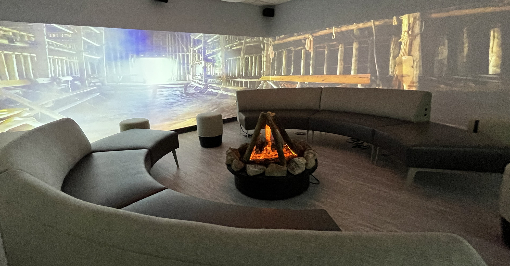 A panoramic view of an immersive room at OISE with couches and a sacred fire in the middle.