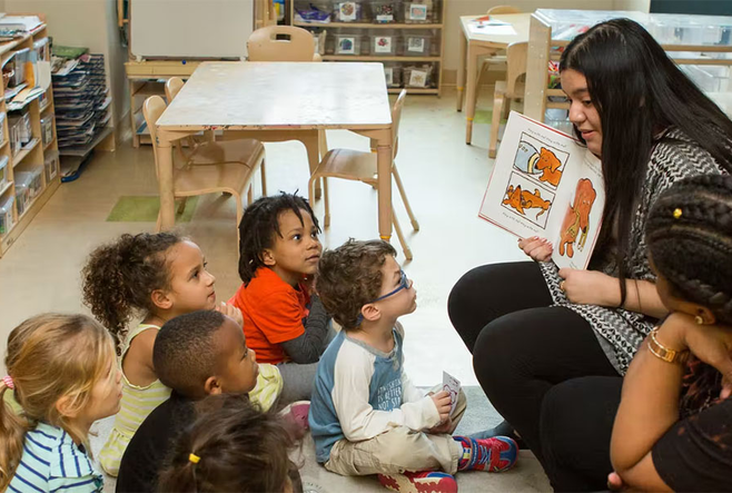 An educator showing a children's book to a group of children.