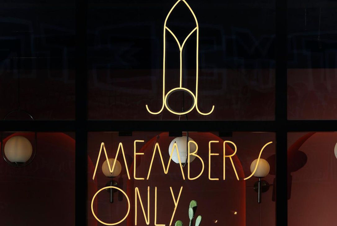 A neon sign on the outside of Members Only Waffle House.