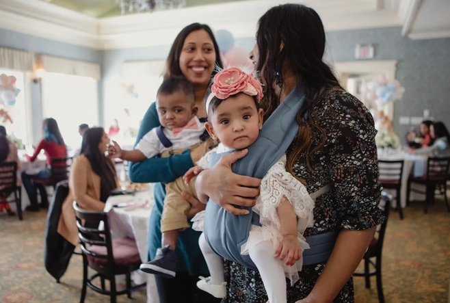 Shakina Rajendram, right, holds her daughter, Adiah, while her sister-in-law, Sharon Nadarajah, holds Adiah’s twin brother, Adrial, at the twins’ first birthday celebration.