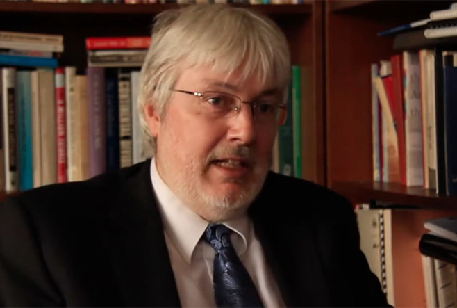 Glen Jones seated with a background of books behind him.