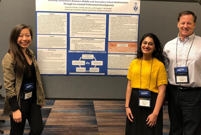 Three individuals stand in front of a research poster, smiling.