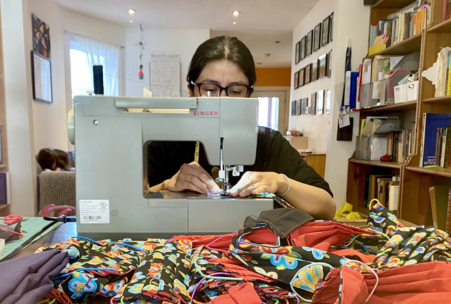 A woman with a sewing machine, making masks.