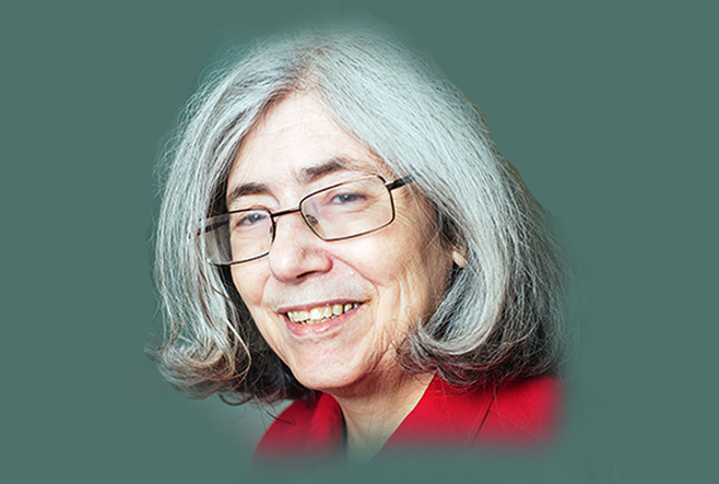 Woman with short grey hair and red top, smiling.