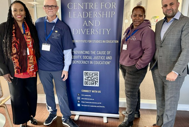 Image of CLD Chair and Attendees along side a CLD Sign