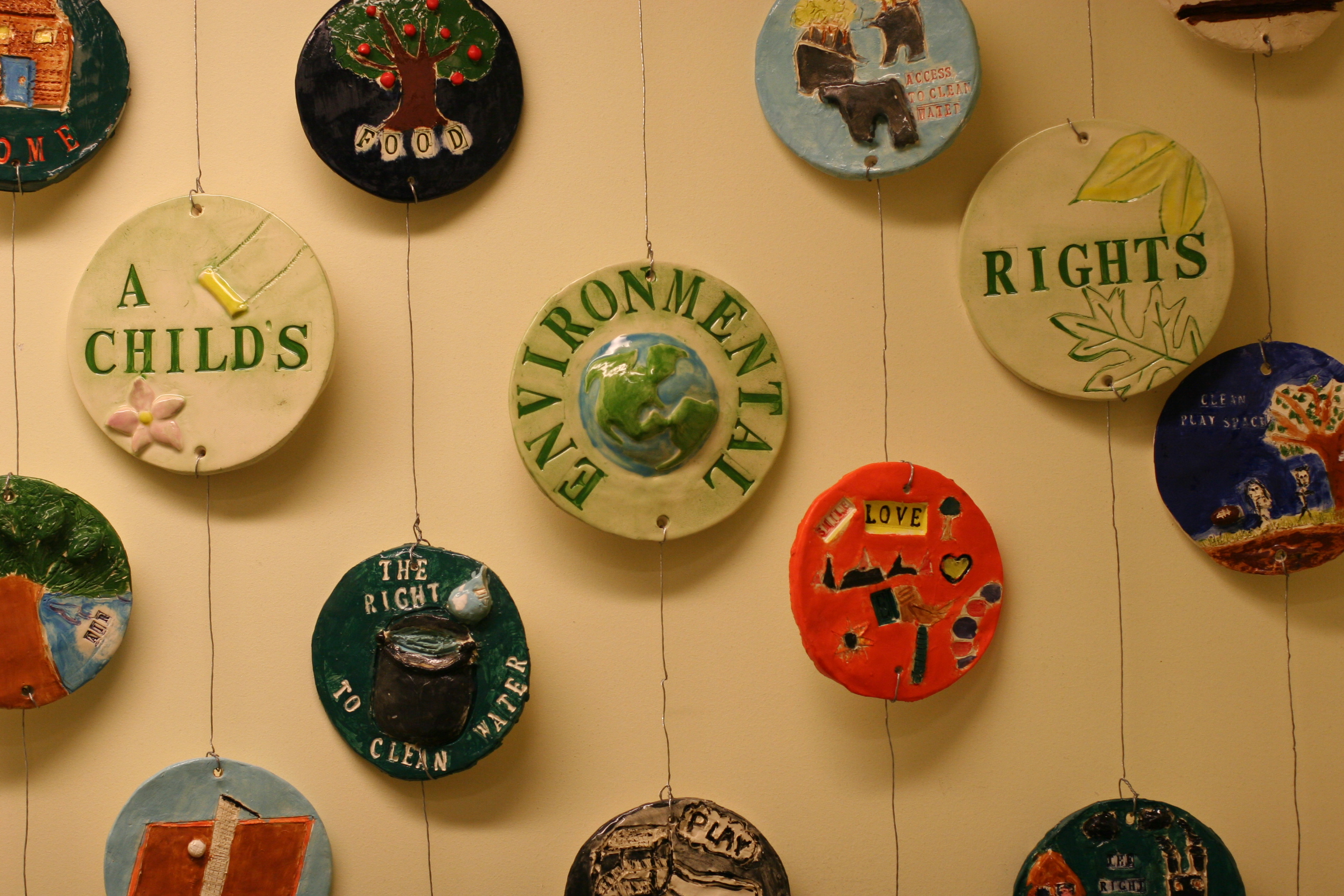 several round tiles installed on the wall with paintings and drawings about environmental rights of the child