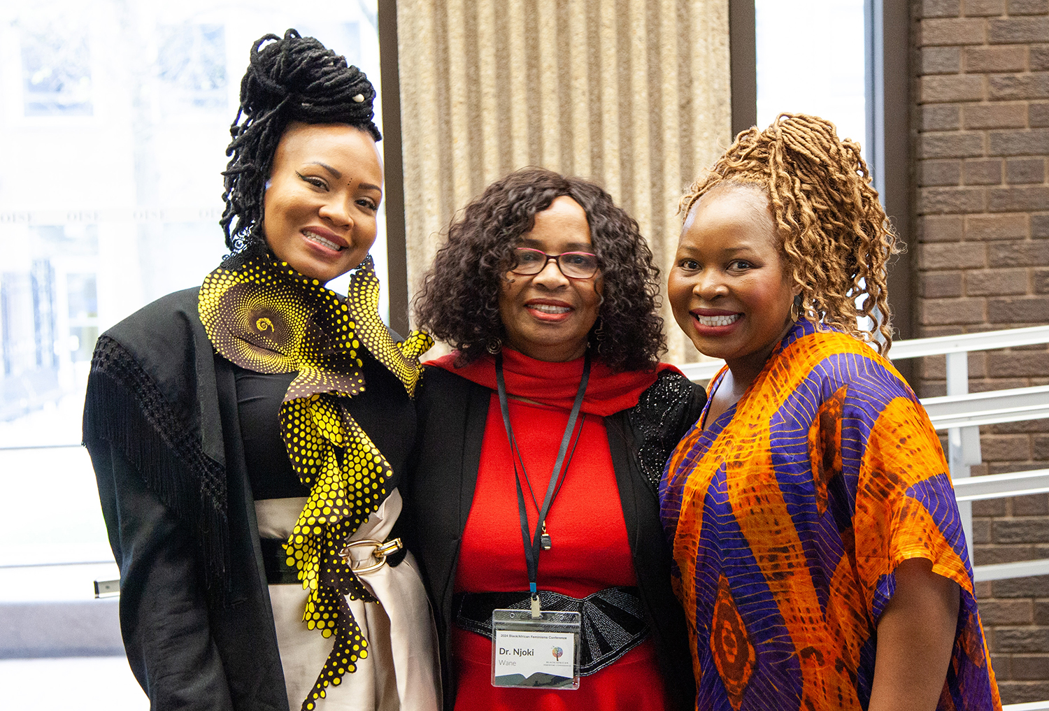 Three Black women are smiling at the camera