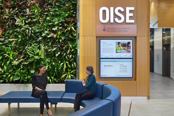 Two individuals sitting in the OISE lobby