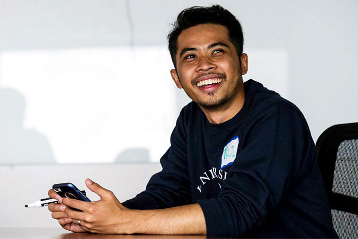 A student smiling and holding a cellphone.