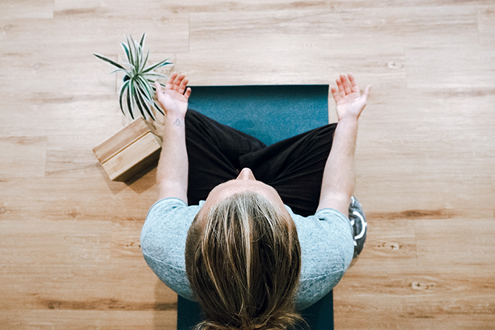 A person meditating on a wooden floor.