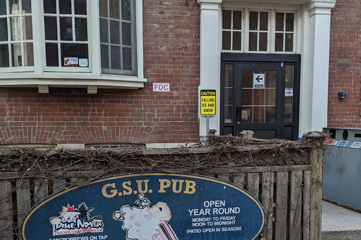 exterior of a brick building with an entrance door and a sign 