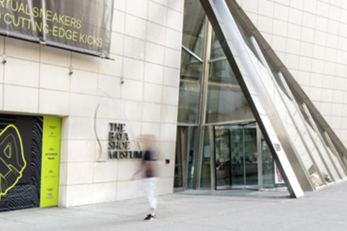 Glass entry door to concrete building with blurred image of human standing in front