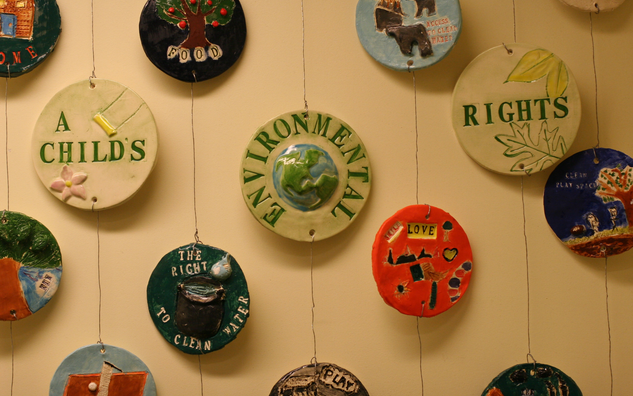 several round tiles installed on the wall with paintings and drawings about environmental rights of the child