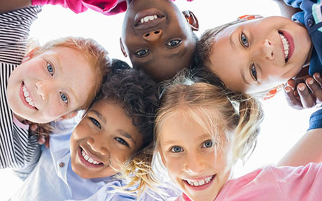 Children smiling and looking directly into a camera. 