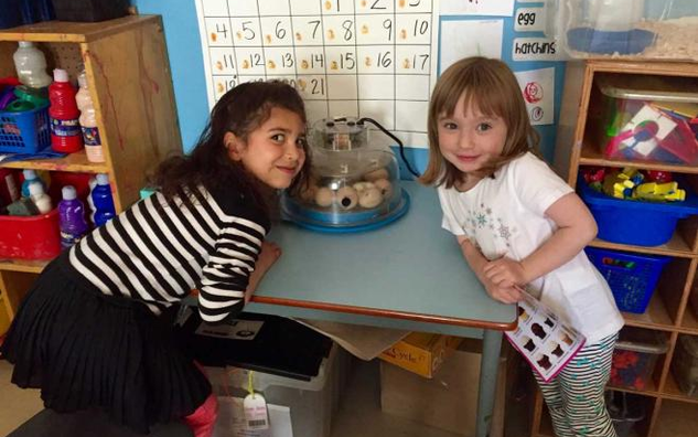 Two JICS students leaning on a table.