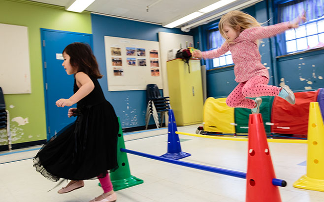 Two students jumping around in a JICS classroom. 