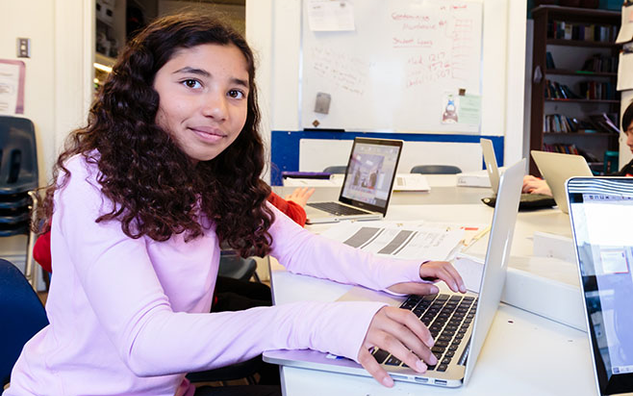 A JICS student typing on a laptop keyboard.