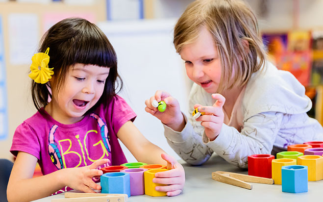 Two JICS students playing with colourful block toys.