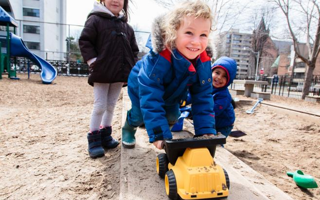 Two children playing outside in a sandbox. 