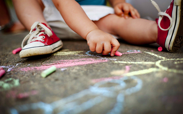 Child drawing with chalk on sidewalk