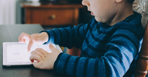 A child using their fingers to scroll on a tablet.