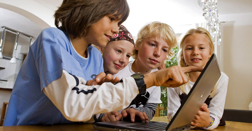 Four children crowded around a laptop screen.