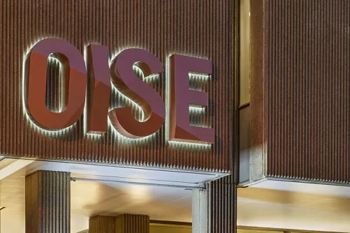 The OISE building sign illuminating at night.