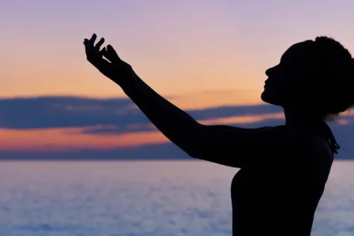 A person meditating by the ocean.