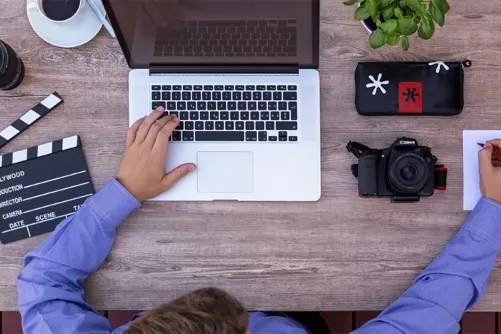 A person typing with their left hand, and writing with their right at a desk.